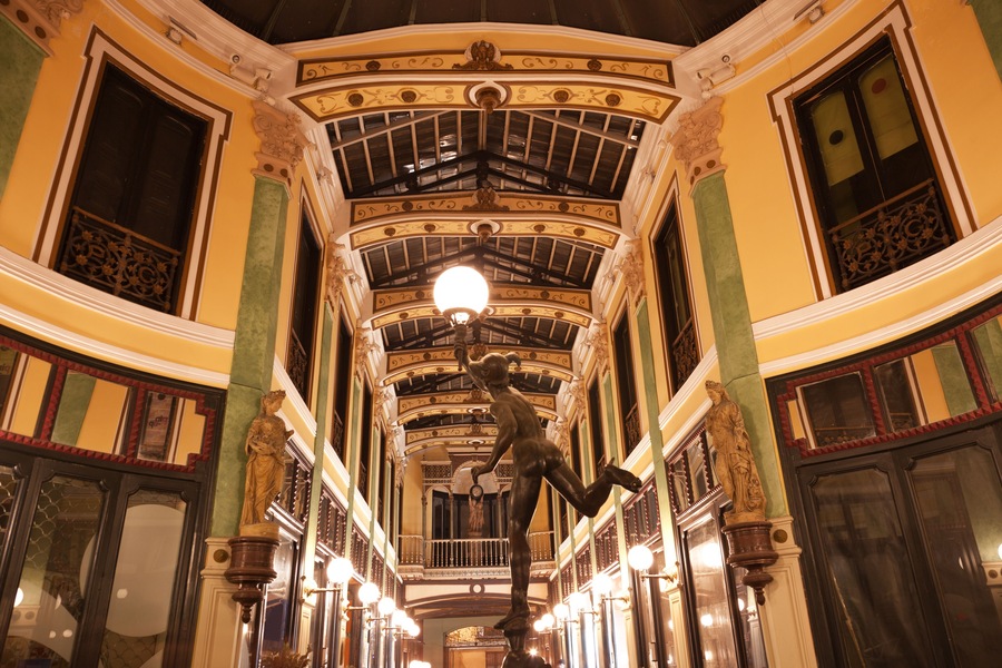 An ornate interior with a high ceiling, decorative moldings, and a central light fixture.
