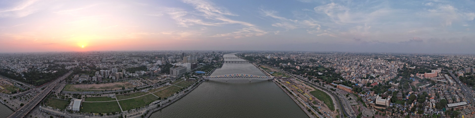 A river flowing through a city with a bridge in the distance and a sunset in the sky.