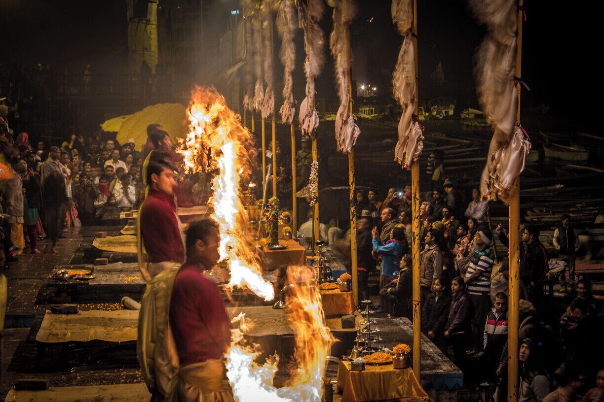 Un mercato all'aperto di notte, con un grande fuoco al centro, circondato da persone e bancarelle.