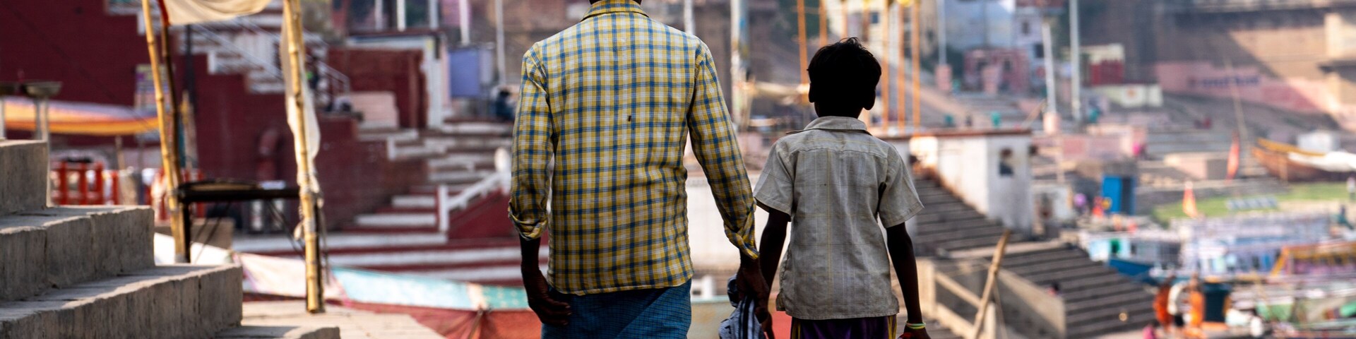 Un hombre y un niño caminando por una calle con escalones que conducen a una zona montañosa al fondo.