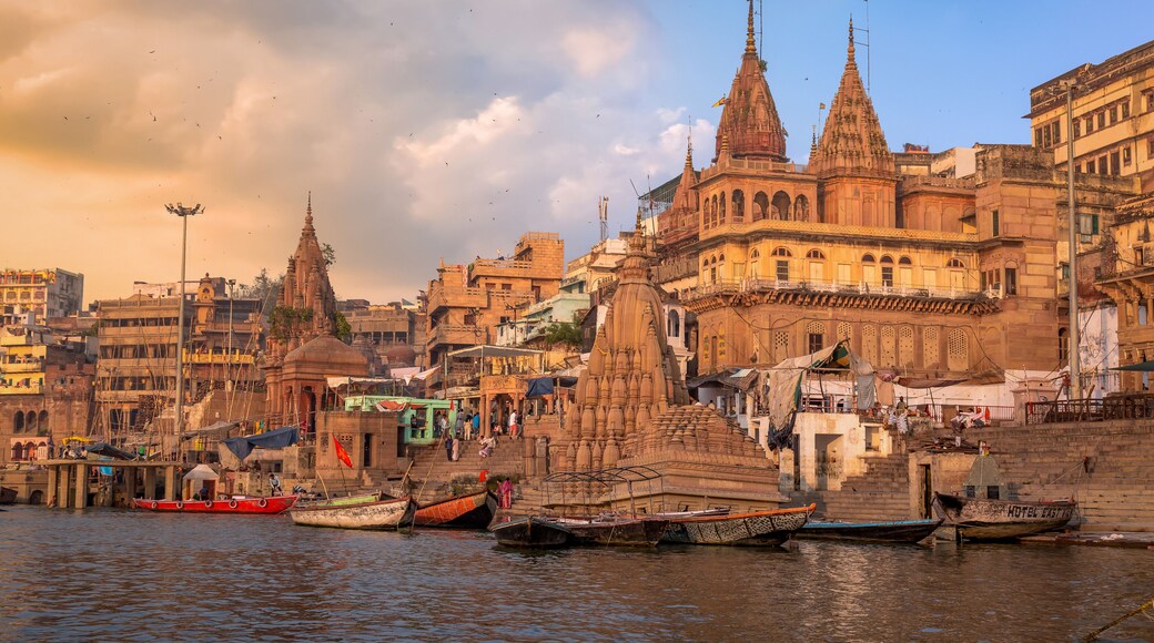 Varanasi city with old architectural buildings and temples along the Ganges river ghat as viewed from a boat at sunset.