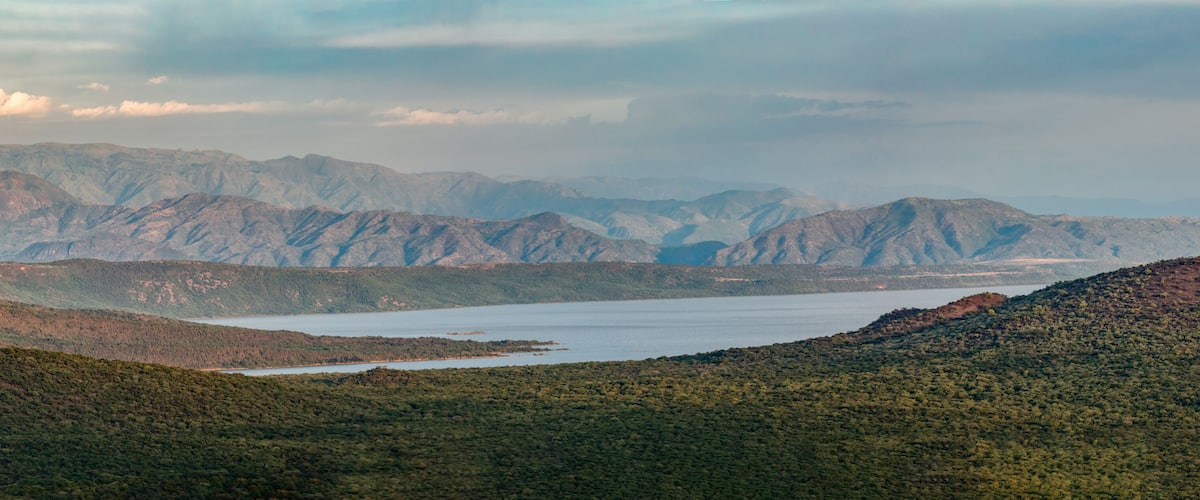 A mountainous landscape with a lake and dense forest.