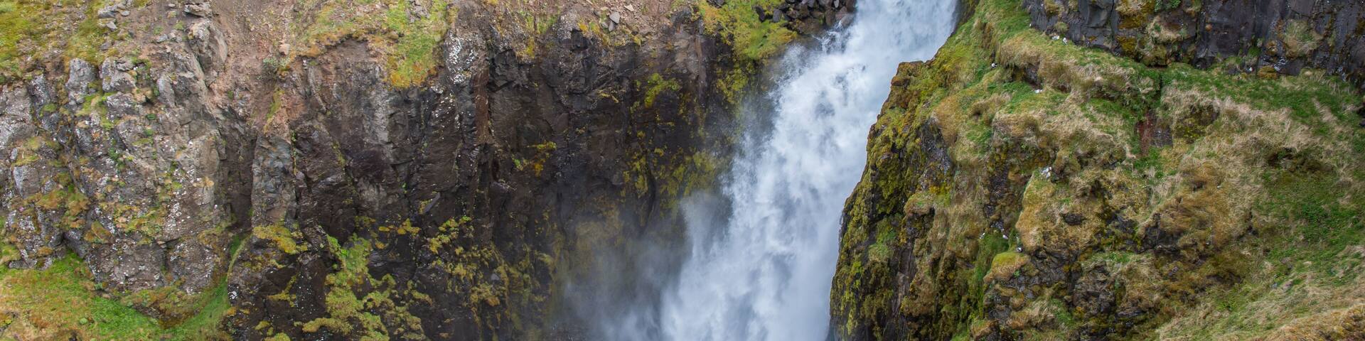 A waterfall cascading down a rocky cliff surrounded by green vegetation.