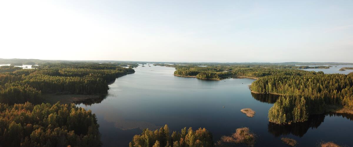 A river winding through a dense forest with several islands and a distant shoreline.