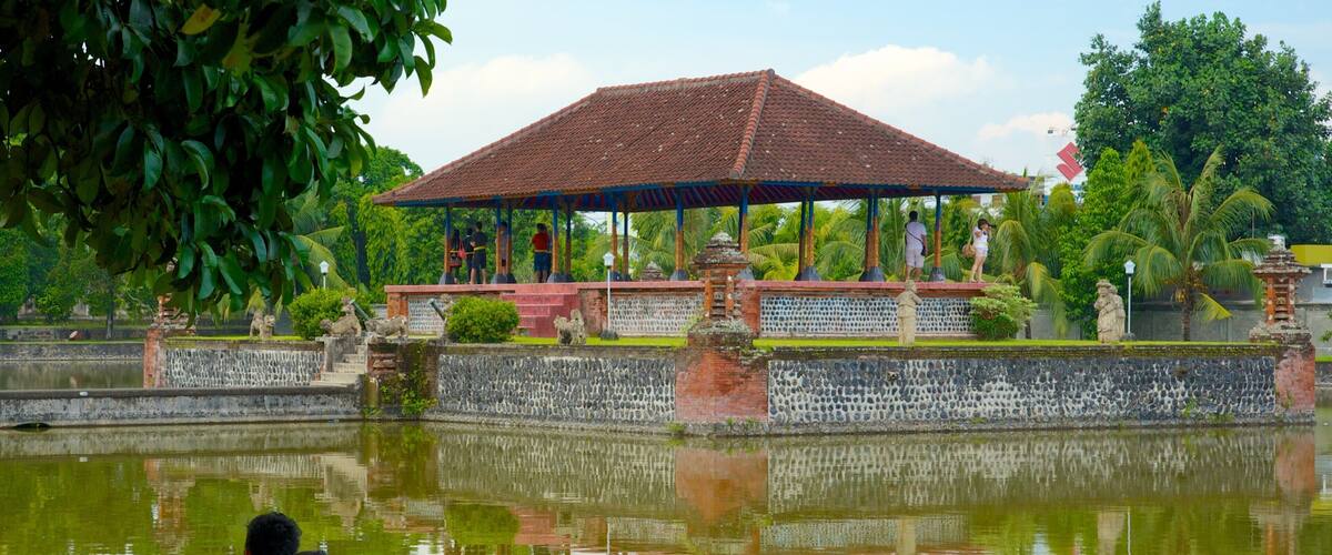 A traditional pavilion with a tiled roof, surrounded by a stone wall and a calm pond.