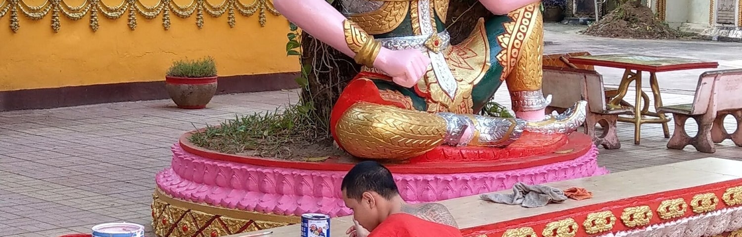 A monk touching up the gold leaf at Wat Si Muang Vientiane