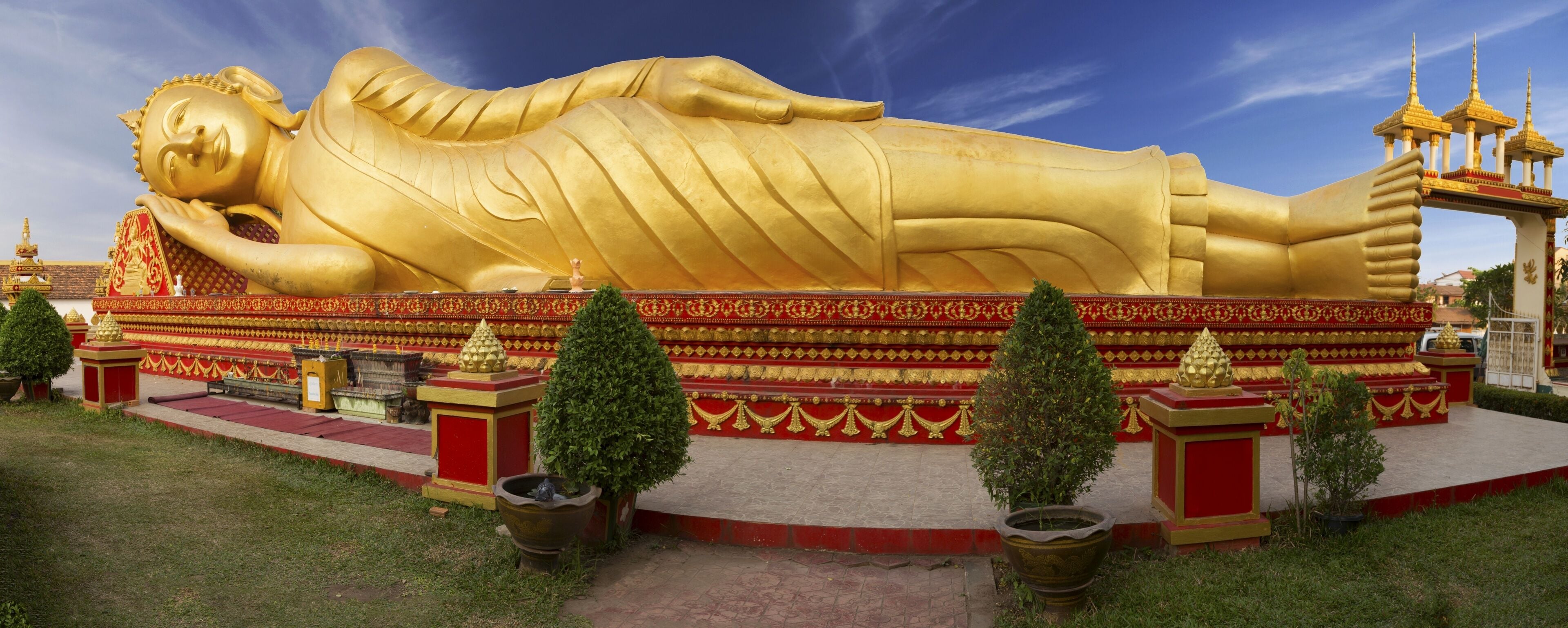 Wide Panoramic View of Reclining Gold Covered Buddha Statue or the Great Stupa, a sacred Buddhist Monument in Pha That Luang, Vientiane, Laos Capital