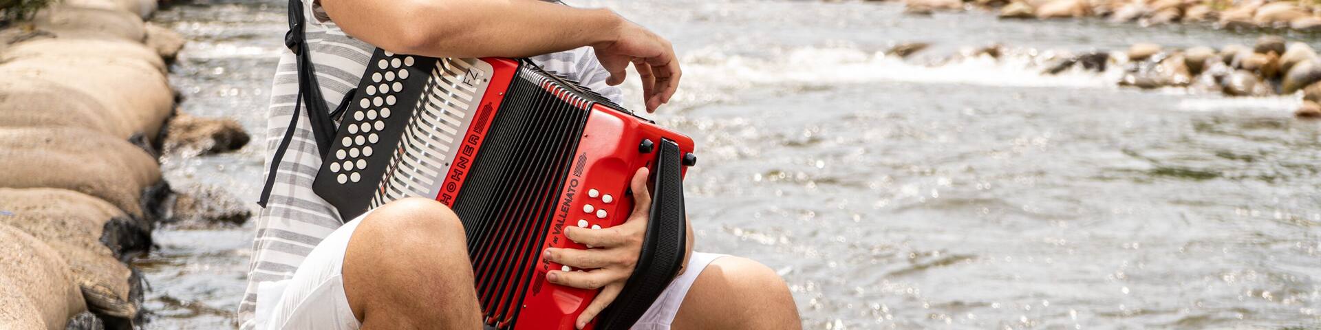 Joven tocando el acordeon a orillas del rio guatapuri en valledupar
