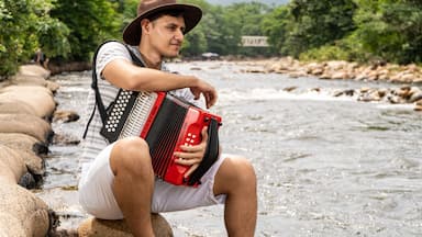 Joven tocando el acordeon a orillas del rio guatapuri en valledupar