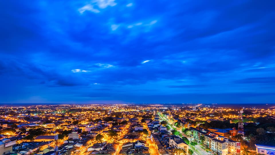 A cityscape at dusk with a vibrant sky and illuminated streets.