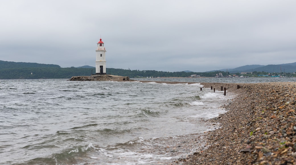 An old lighthouse with a red roof on the seashore. Seascape with copy space. Postcard from travel. Tokarevsky Lighthouse. Vladivostok, Russia.