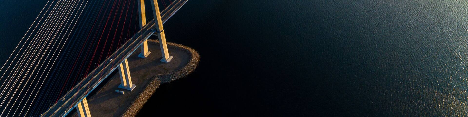 Amazing zooming out aerial view of the Russky Bridge, the world's longest cable-stayed bridge, and the Russky (Russian) Island in Peter the Great Gulf in the Sea of Japan. Sunrise. Vladivostok, Russia
