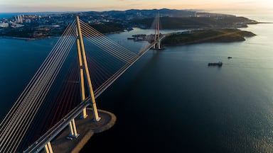 Amazing zooming out aerial view of the Russky Bridge, the world's longest cable-stayed bridge, and the Russky (Russian) Island in Peter the Great Gulf in the Sea of Japan. Sunrise. Vladivostok, Russia