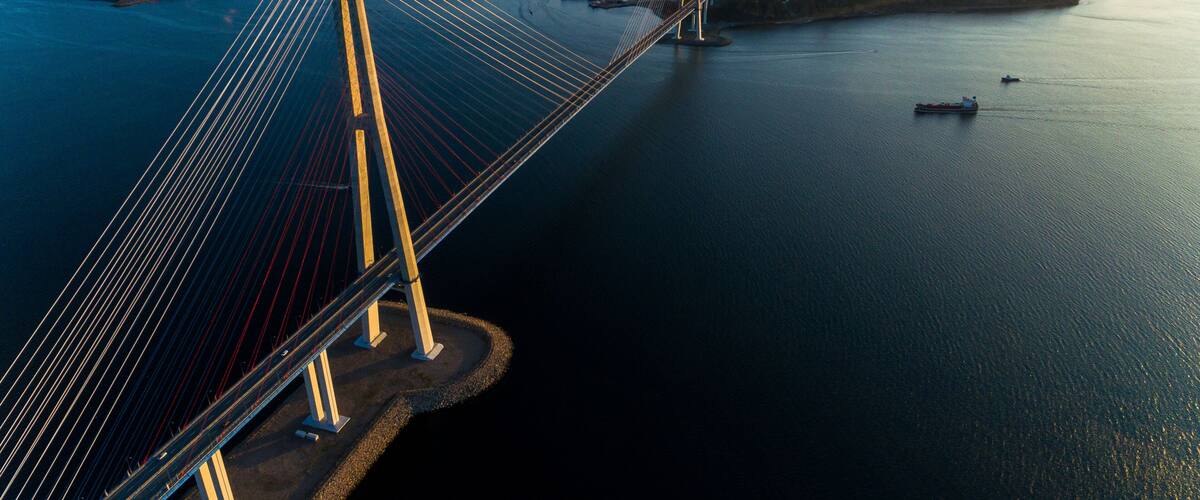A cable-stayed bridge spanning a body of water with a cityscape in the background.