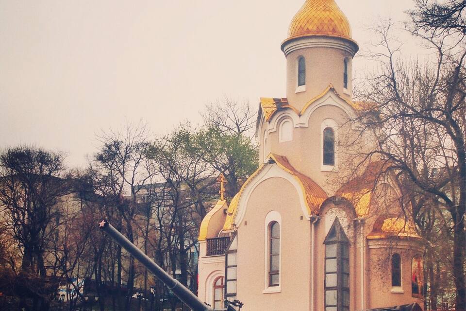 Una iglesia con una cúpula dorada y una cruz en la parte superior, rodeada de árboles.