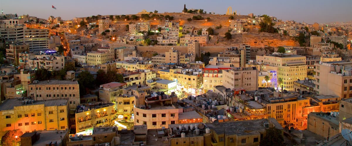 A densely populated urban area with a mix of residential and commercial buildings, a prominent hill with a mosque, and a bridge in the background.