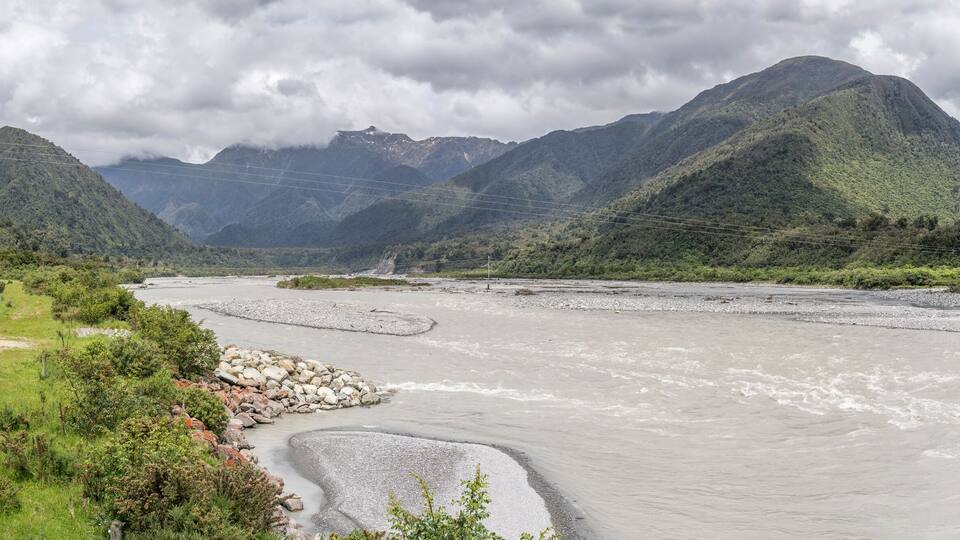 A river flowing through a mountainous landscape with rocky banks and lush greenery.