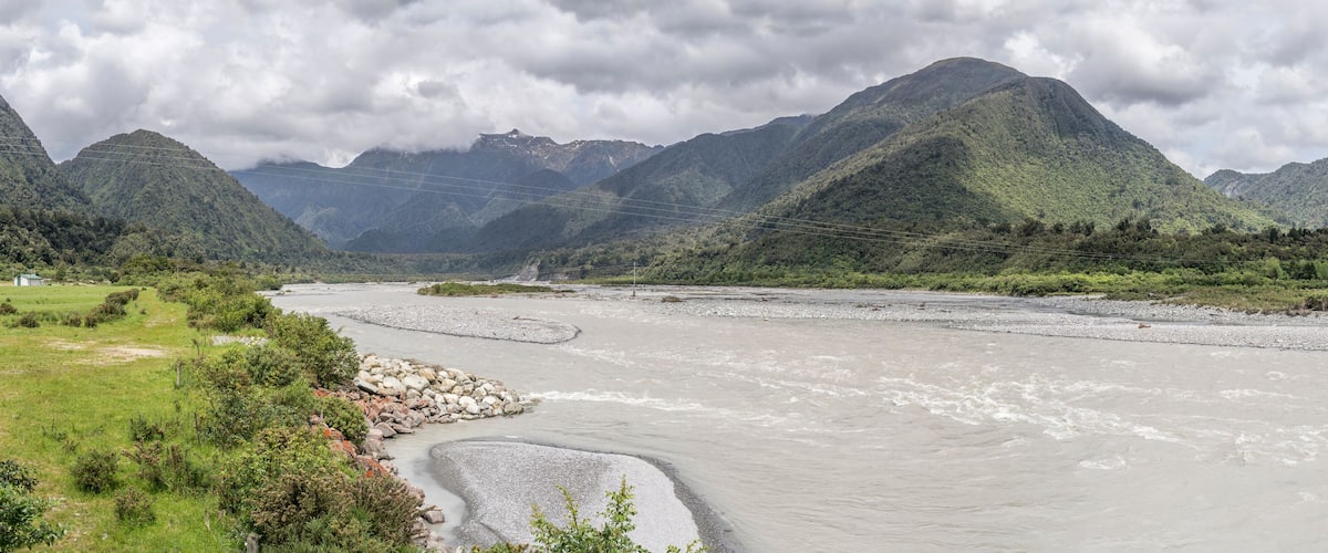 A river flowing through a mountainous landscape with rocky banks and lush greenery.