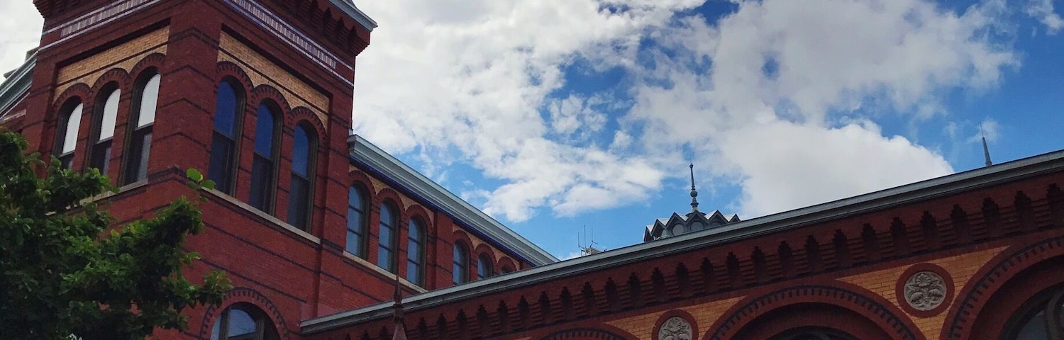 A red brick building with a pointed tower and arched windows.