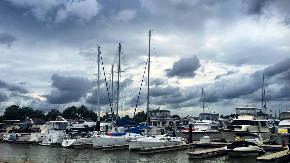 A marina with various boats docked under a cloudy sky.