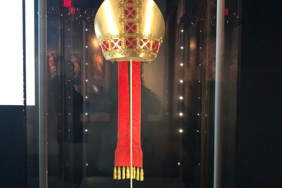 A traditional lantern with a red tassel hanging from a white pole inside a glass display case.