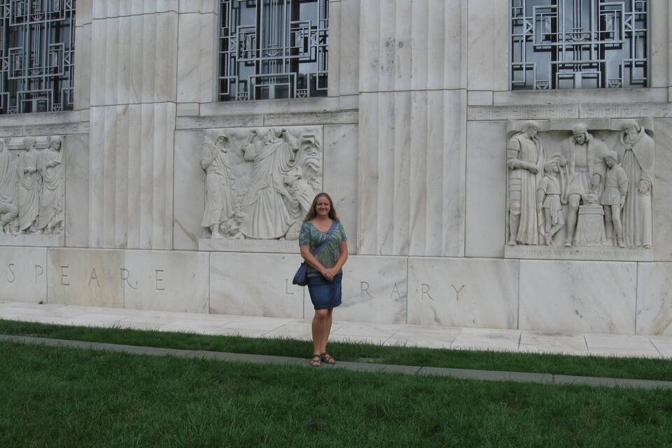 A person standing in front of a building with inscriptions and sculptures.