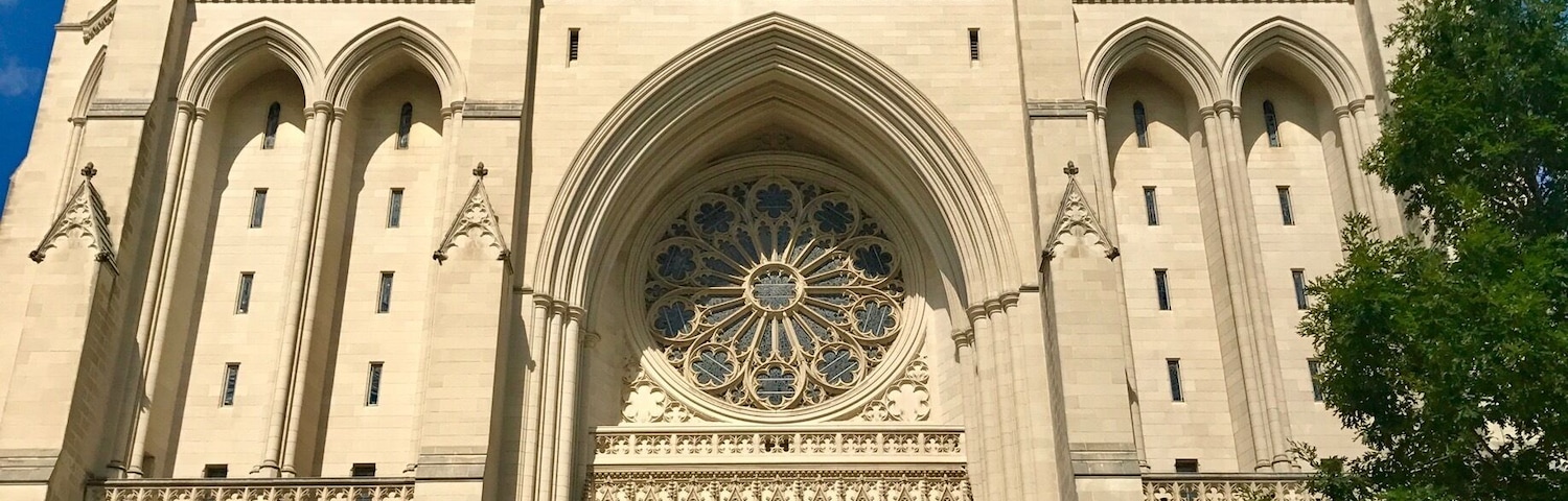 A large Gothic cathedral with twin towers, intricate stained glass windows, and a prominent rose window.
