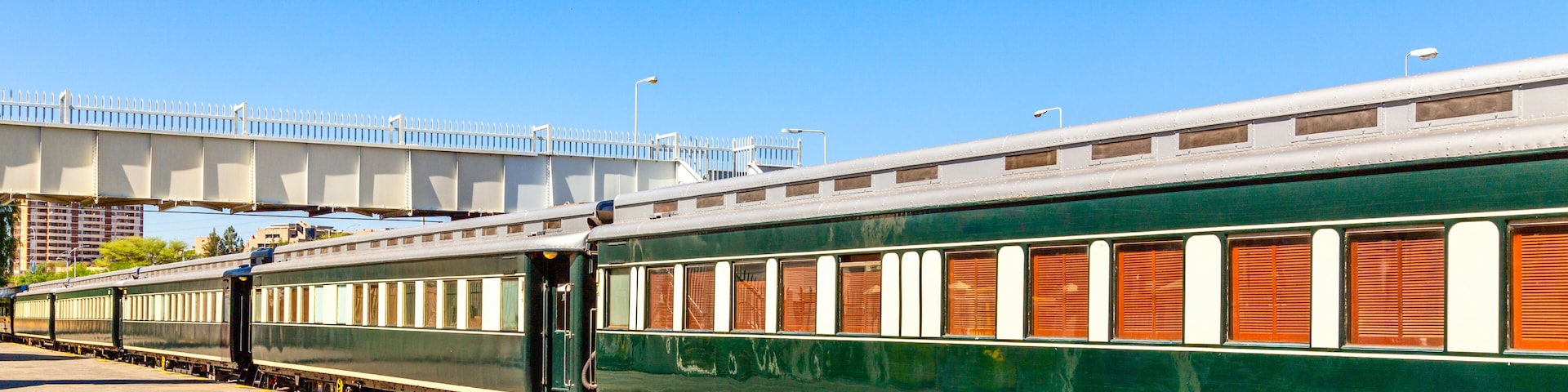 Un tren verde con ventanas marrones estacionado en una estación.