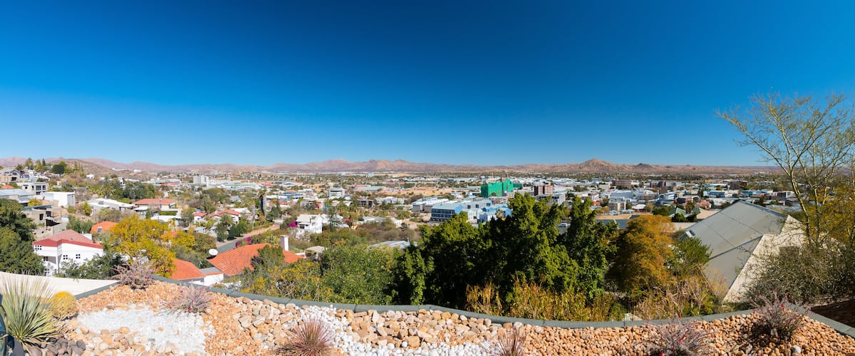 A town with a mix of residential and commercial buildings, surrounded by mountains and trees.