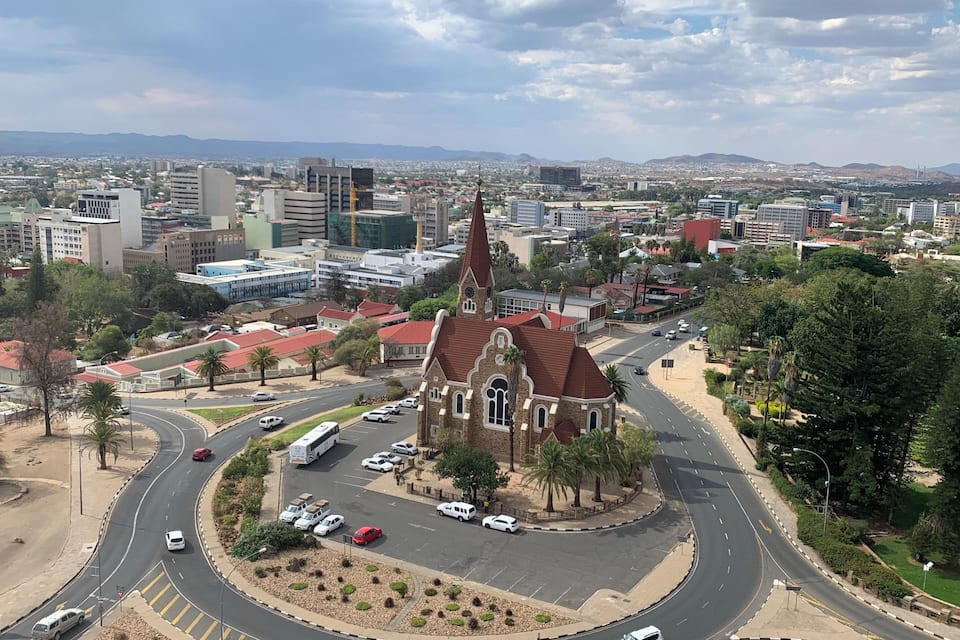 A cityscape with a prominent church, a roundabout, and distant mountains.