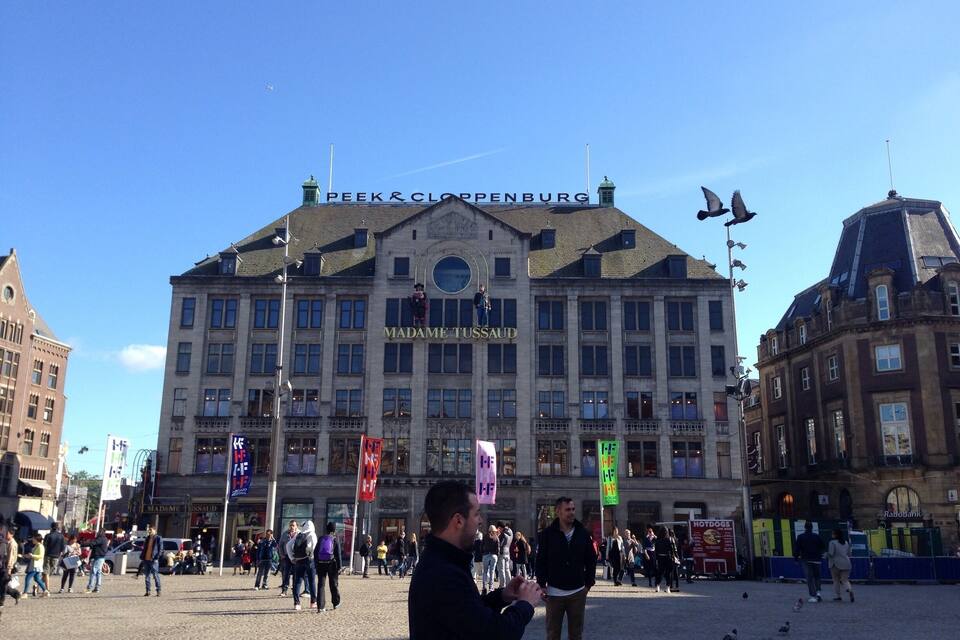 A large building with 'Madame Tussaud' written on it, surrounded by people and pigeons.