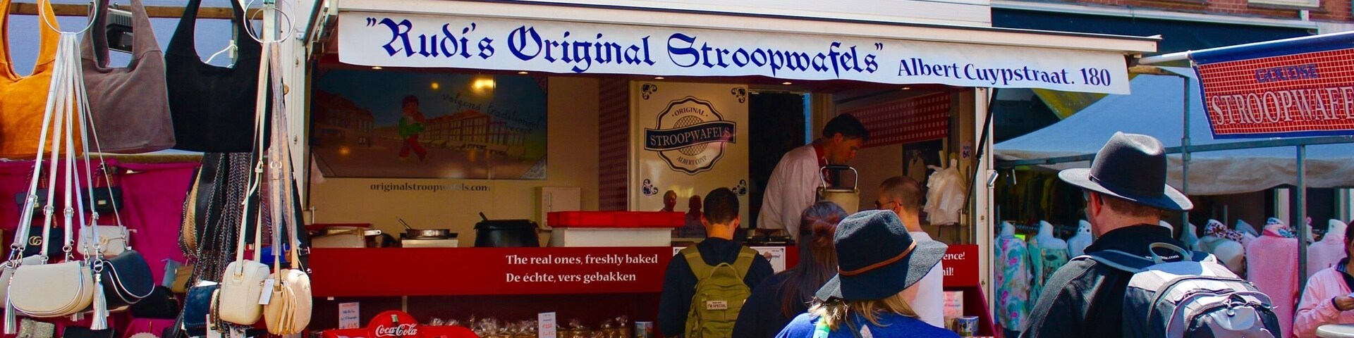 Um mercado de rua com uma banca chamada "Rudi's Original Stroopwafels" na Albert Cuypsstraat, 180, Amsterdã.