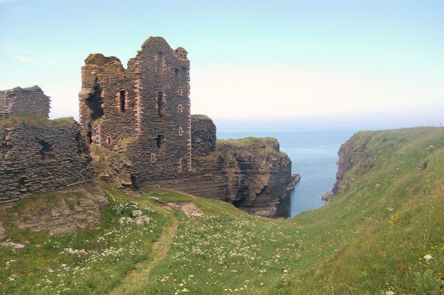A ruined castle on a cliff overlooking the sea.
