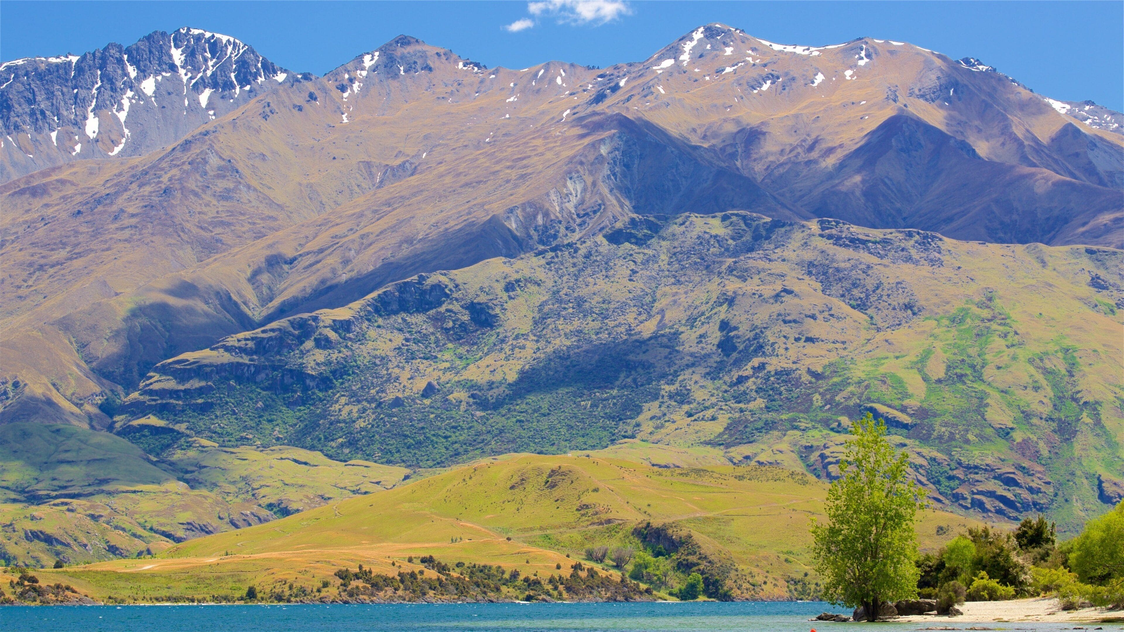 A mountain range with a lake in the foreground and a clear sky.