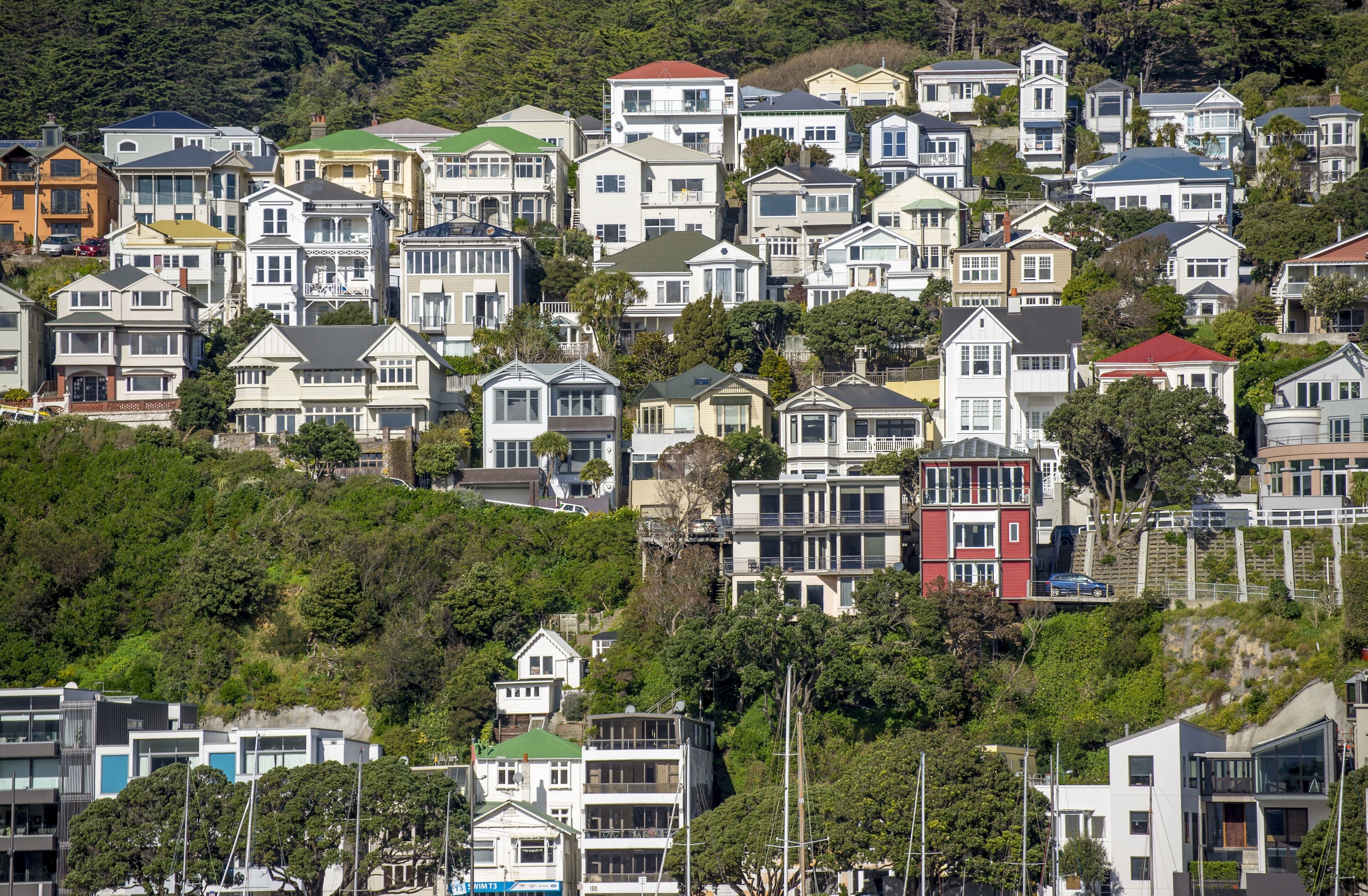 Una zona residencial en una ladera con diversas casas, algunas con tejados rojos, y abundante vegetación.