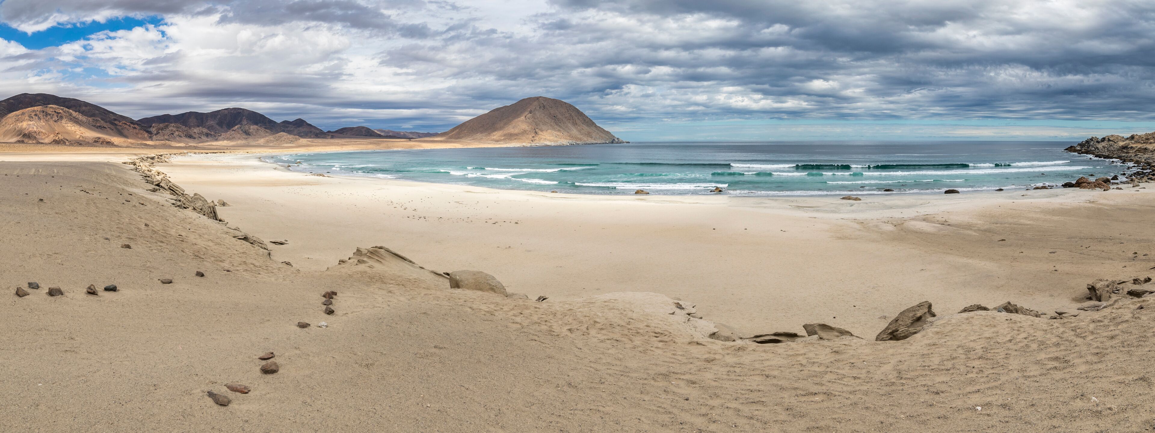 A desert beach with a mountain in the background.