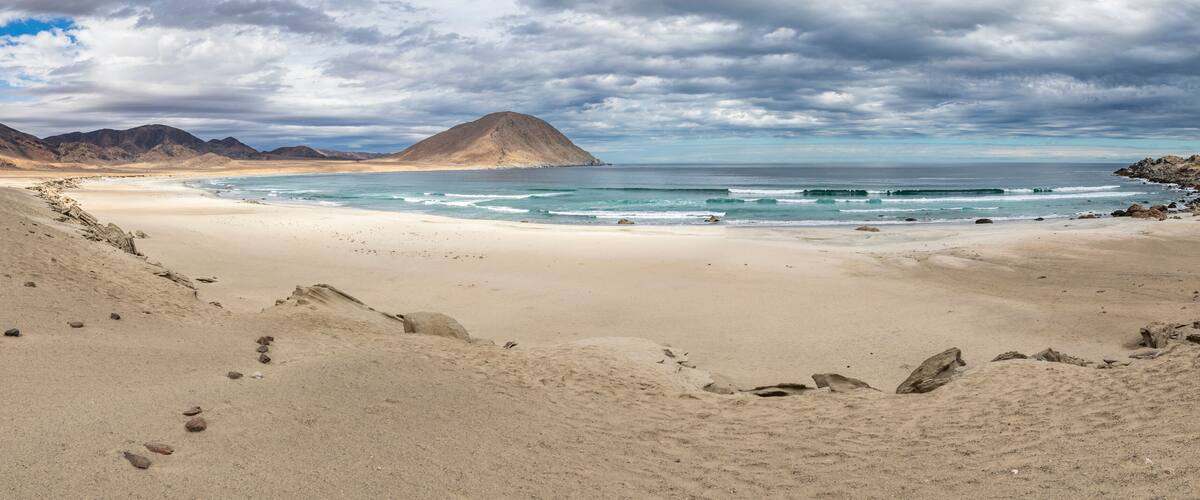 A desert beach with a mountain in the background.