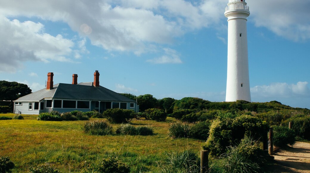 Split Point Lighthouse, Aireys Inlet, Victoria. Scenic landscape of lighthouse and caretaker's cottage in leafy green foliage amidst blue sky.
