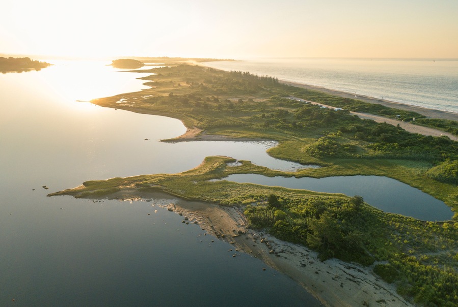 A coastal landscape with a river, ponds, and a beach.