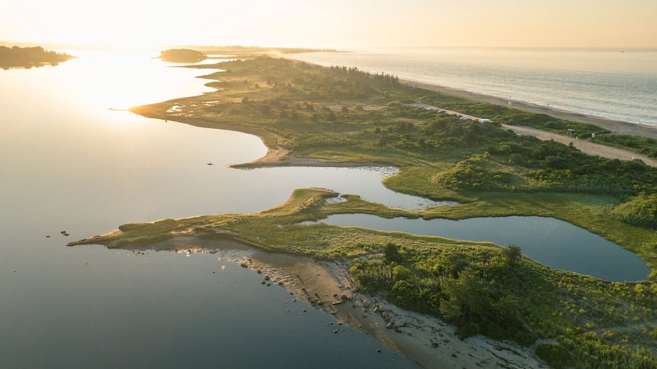 A coastal landscape with a river, ponds, and a beach.