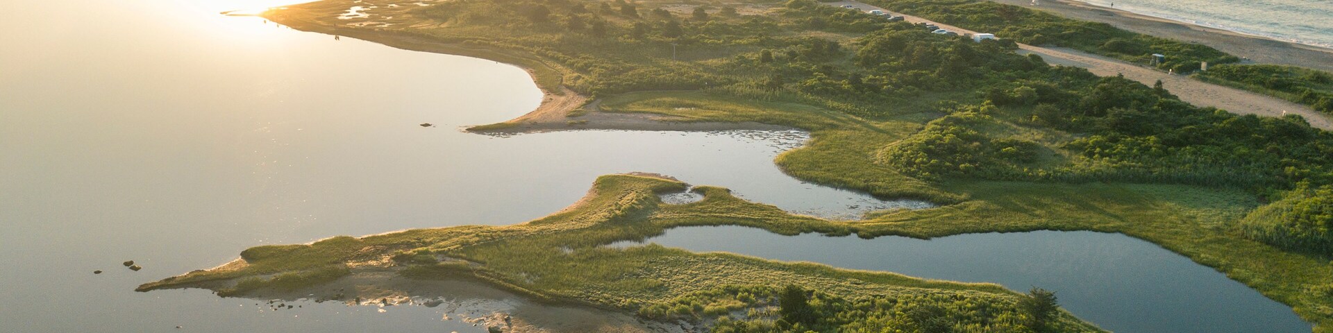 A coastal landscape with a river, ponds, and a beach.