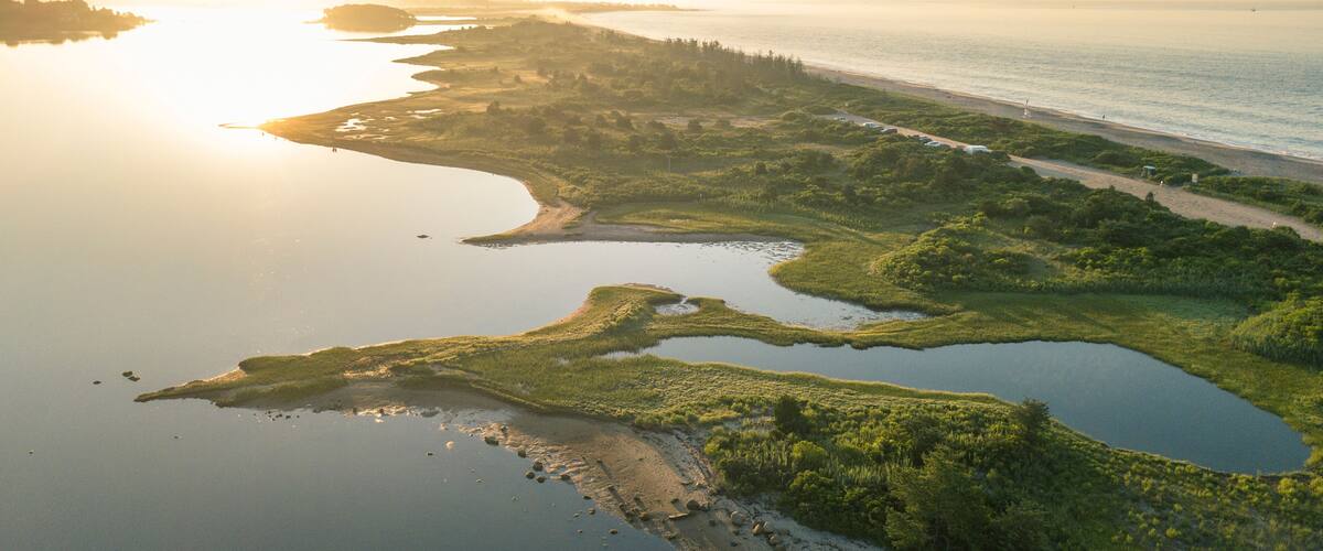 A coastal landscape with a river, ponds, and a beach.