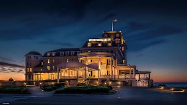 A large, illuminated building with a sign reading "Ocean House" at dusk.