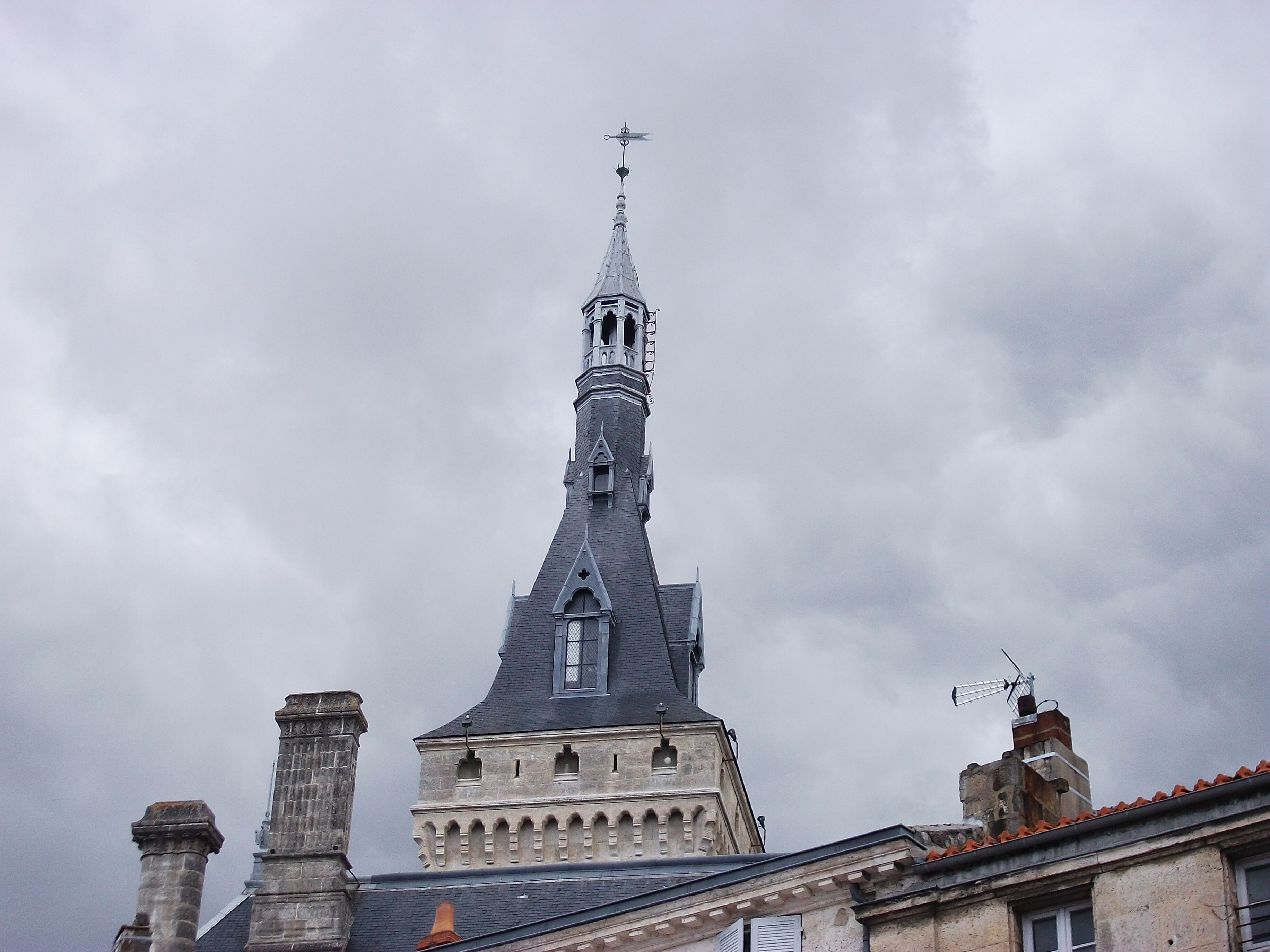 Una iglesia con un campanario alto y una veleta.