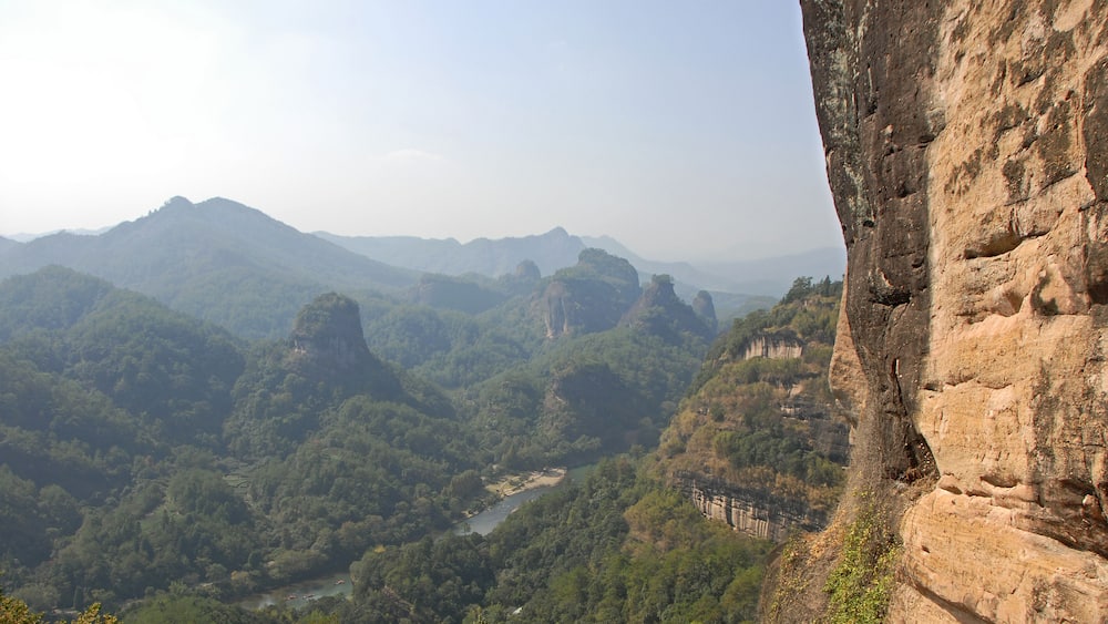 Un paysage montagneux avec une rivière, de vastes forêts et une formation rocheuse remarquable.