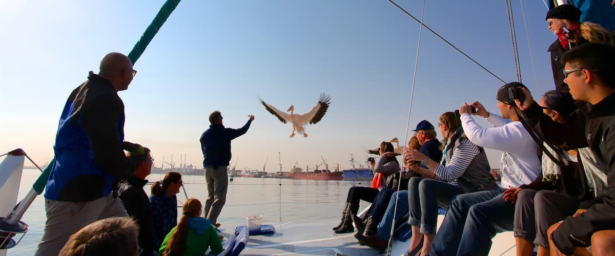 A seaplane taking off from a dock with people watching.