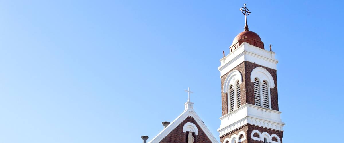 A large brick church with a prominent clock tower and a steeple.
