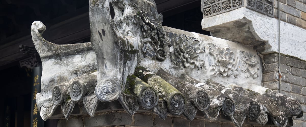 A weathered stone structure with intricate carvings and a lion figure.
