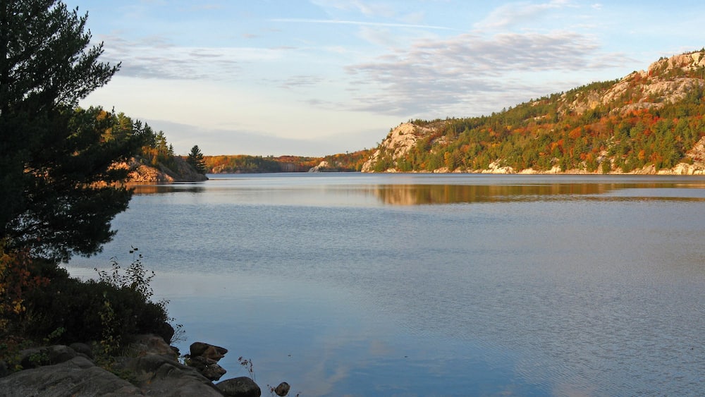 A calm lake with a forested hill in the background.