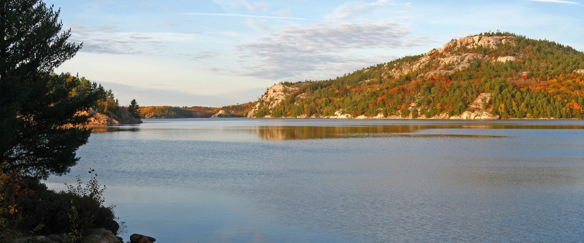 A calm lake with a forested hill in the background.